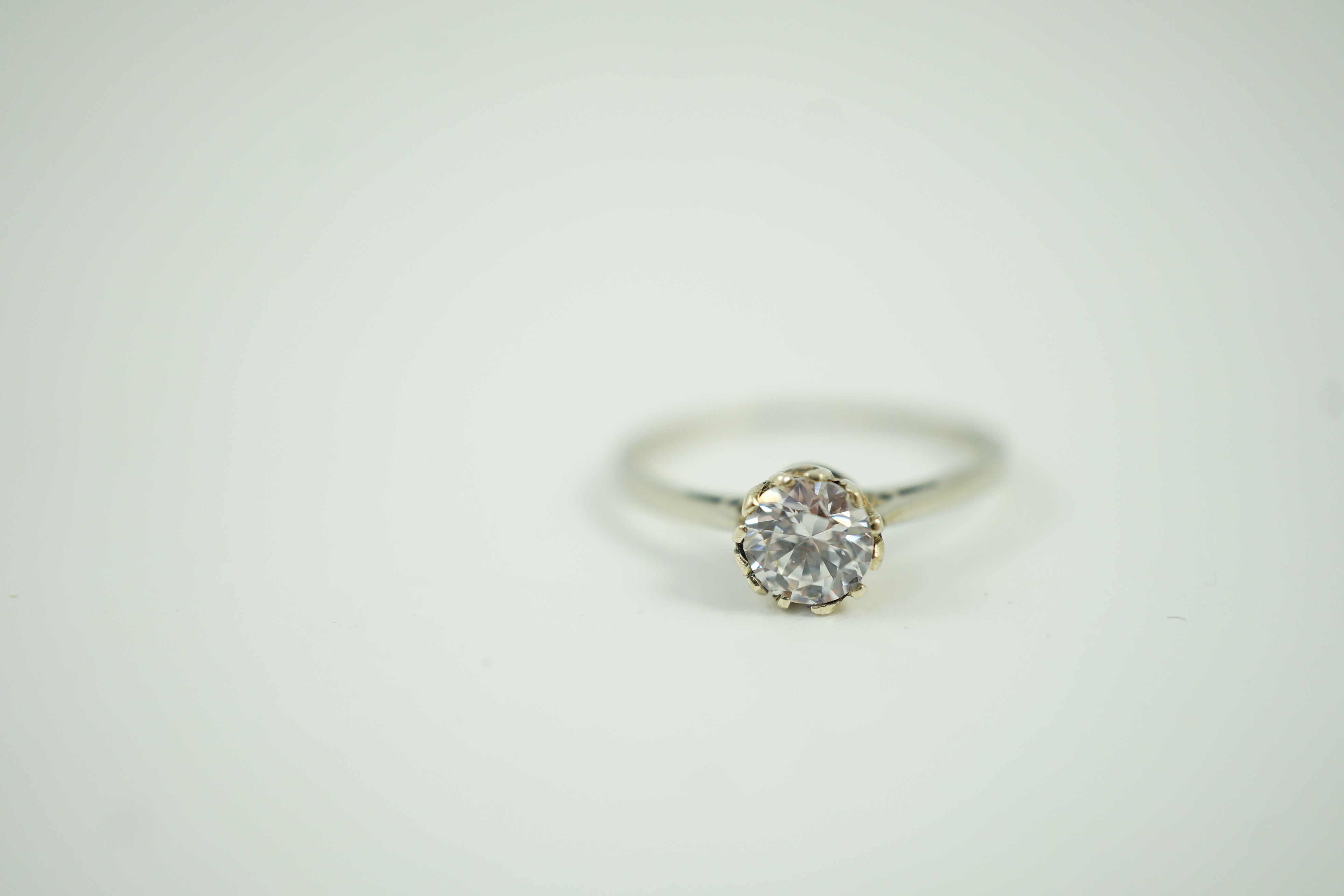 An 18ct and plat set and simulated diamond ring, the stone diameter approx. 4.5mm, size J, gross weight 1.1 grams.